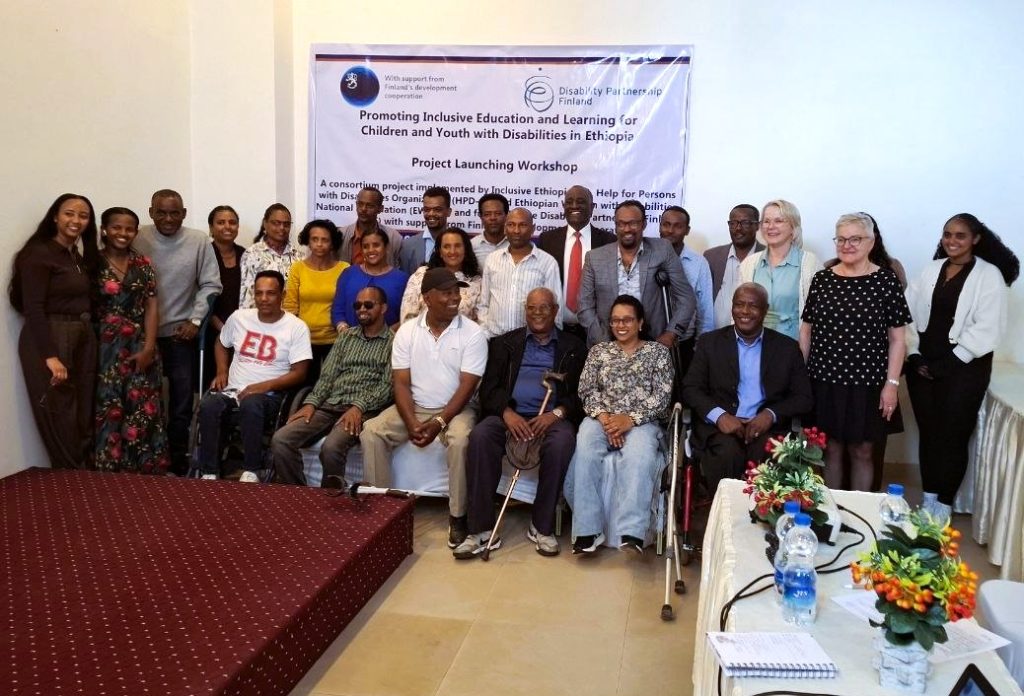 Group at a project-launch workshop in front of an inclusive education and learning banner.